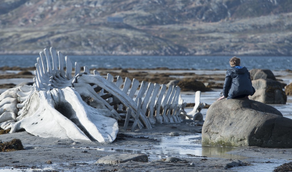 Roma (Sergueï Pokhodaev) sitzt neben einem Walgerippe am Meer der russischen Halbinsel Kola. © Wild Bunch Germany