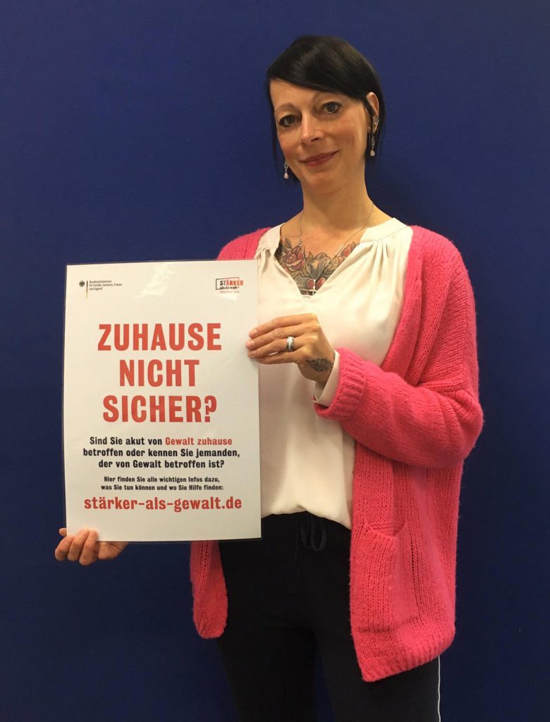 Gleichstellungsbeauftragte Sybille Lüdecke mit einem Plakat der Initiative „Zuhause nicht sicher?“.