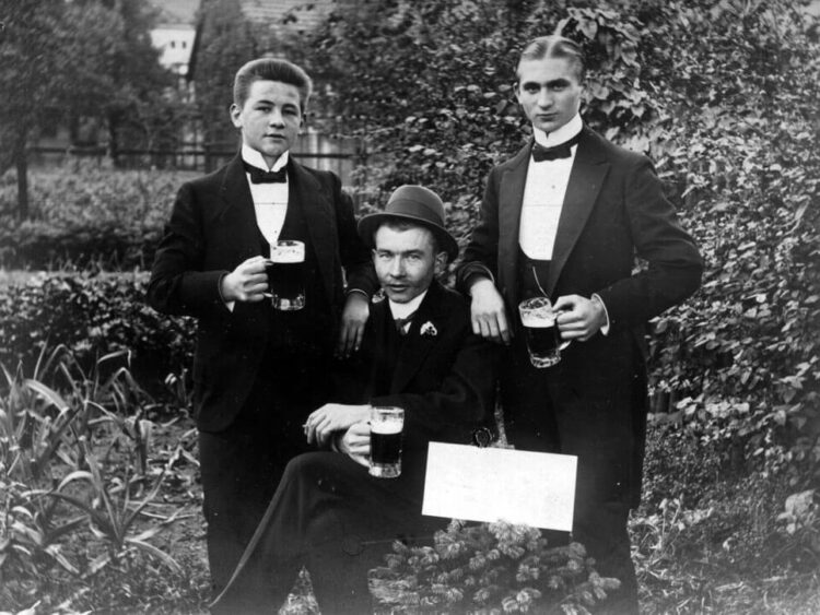 Historisches Foto von drei Männern in Anzügen mit Biergläsern in den Händen