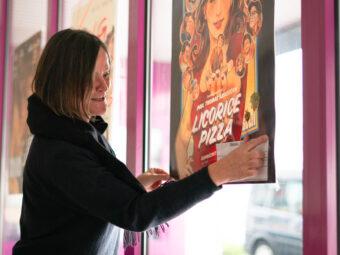 Connie Schwartz bringt ein Filmplakat an