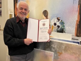 Redzep Memisevic hält eine Urkunde in die Kamera und lächelt